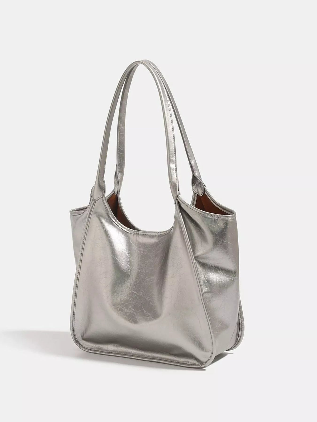 Metallic silver PU leather tote bag with a soft, slouchy silhouette, open top, long shoulder straps, and stitched panel construction.
