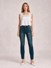 Model stands facing forward in dark blue mid-rise skinny jeans with front pockets, belt loops, button closure, zip fly, subtle fading, and a fitted tapered silhouette.