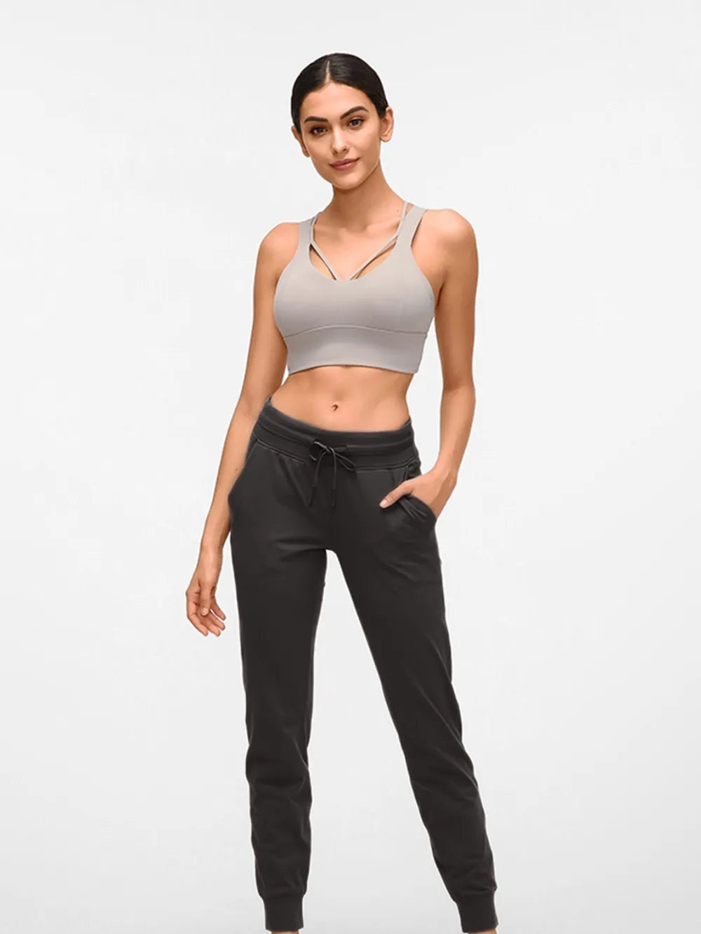 Model poses in black tied joggers with a drawstring waist, side pockets, stretchy tapered legs, and cuffed ankles.