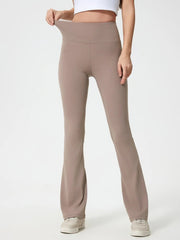 Model wears taupe high waist active pants with a wide supportive waistband, smooth stretch construction, fitted hips and thighs, and gently flared legs.