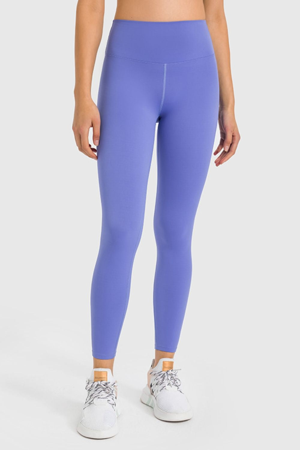 Model wears high-waist ankle-length yoga leggings in vibrant purple with a smooth, stretchy, close-fitting silhouette and visible front seam.