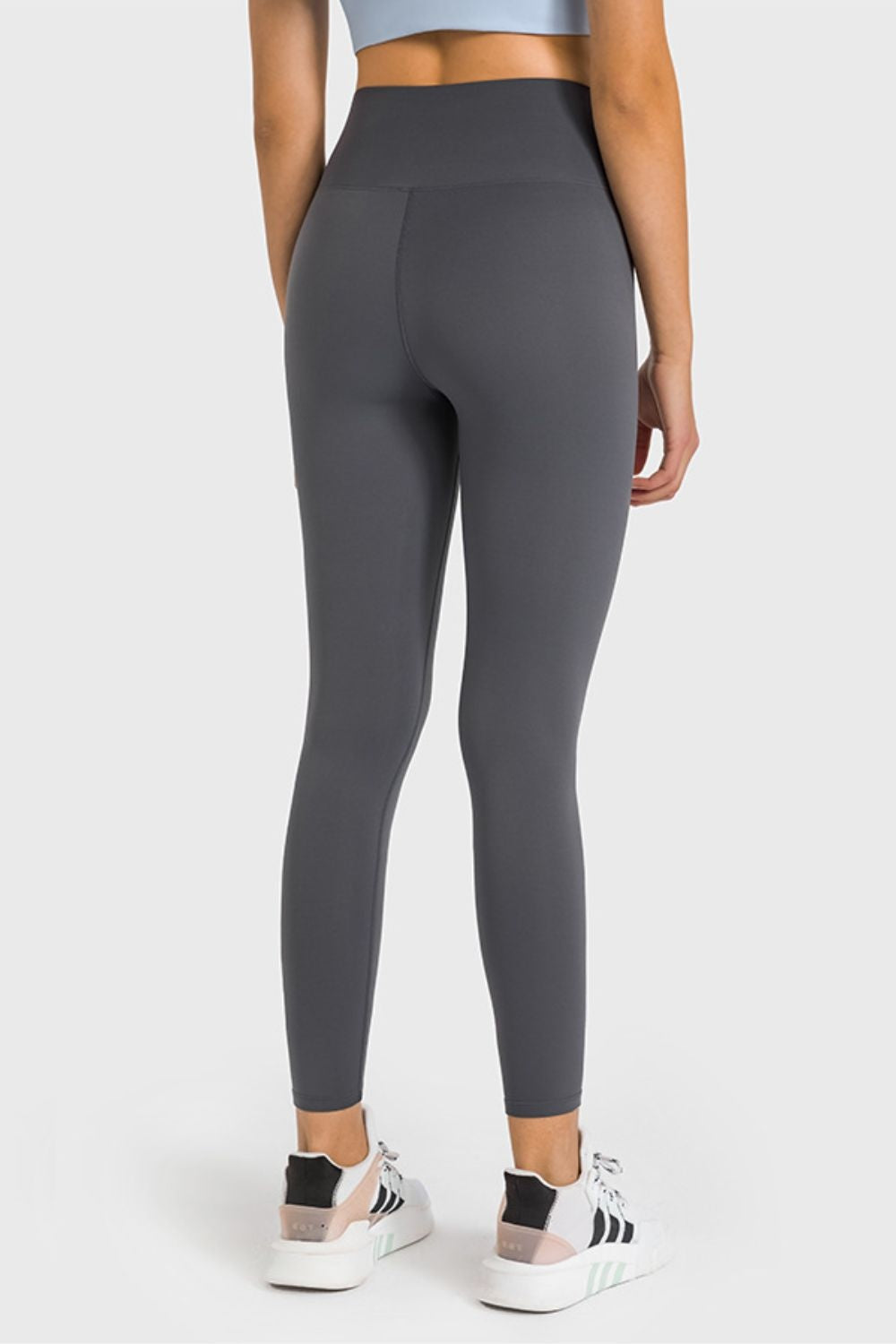 Model shown from the back wearing dark gray high-waist ankle-length yoga leggings with a smooth, stretchy, close-fitting silhouette and wide waistband.