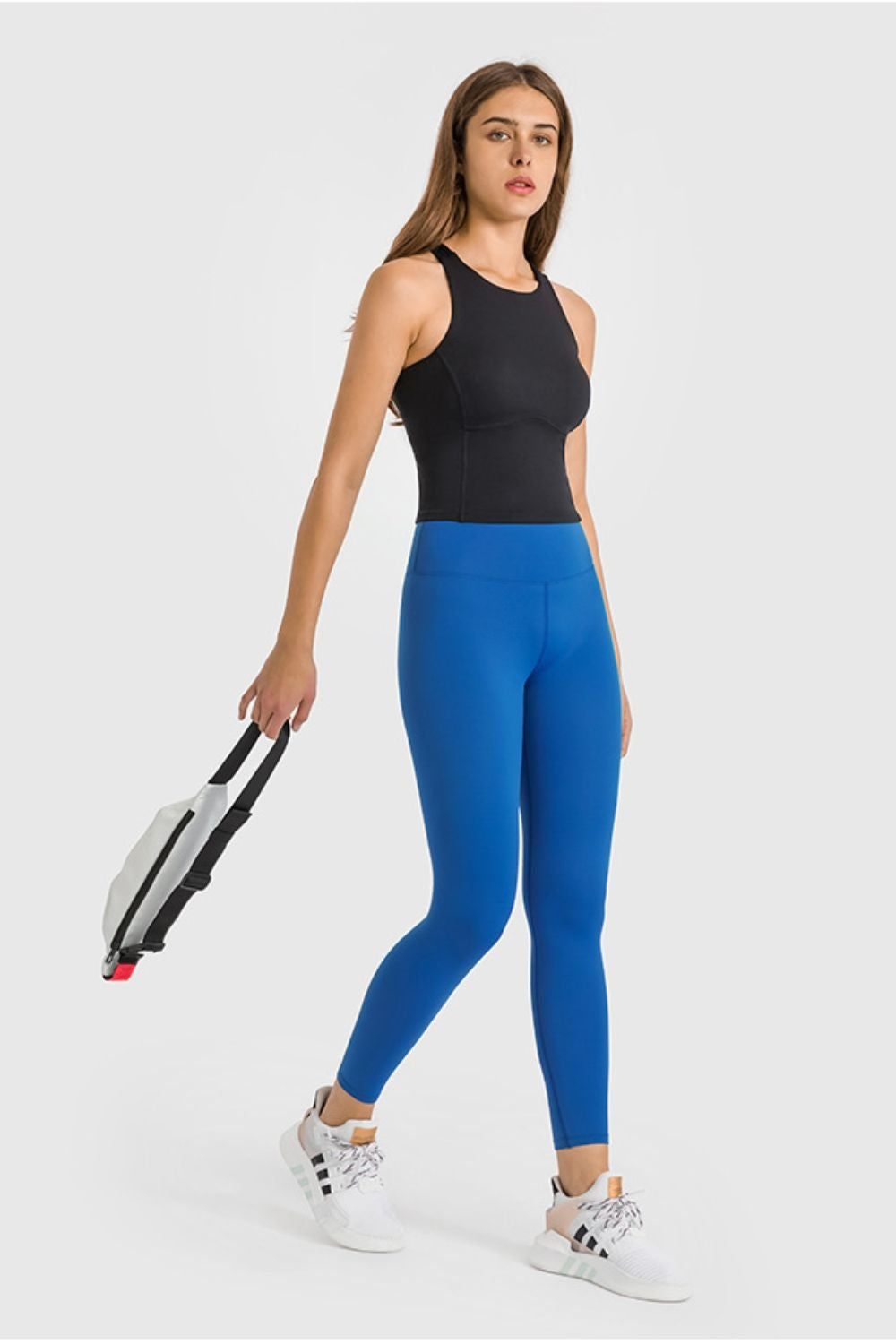 Model wearing bright blue high-waist ankle-length yoga leggings with a smooth, close-fitting stretch silhouette, posing with one leg crossed.