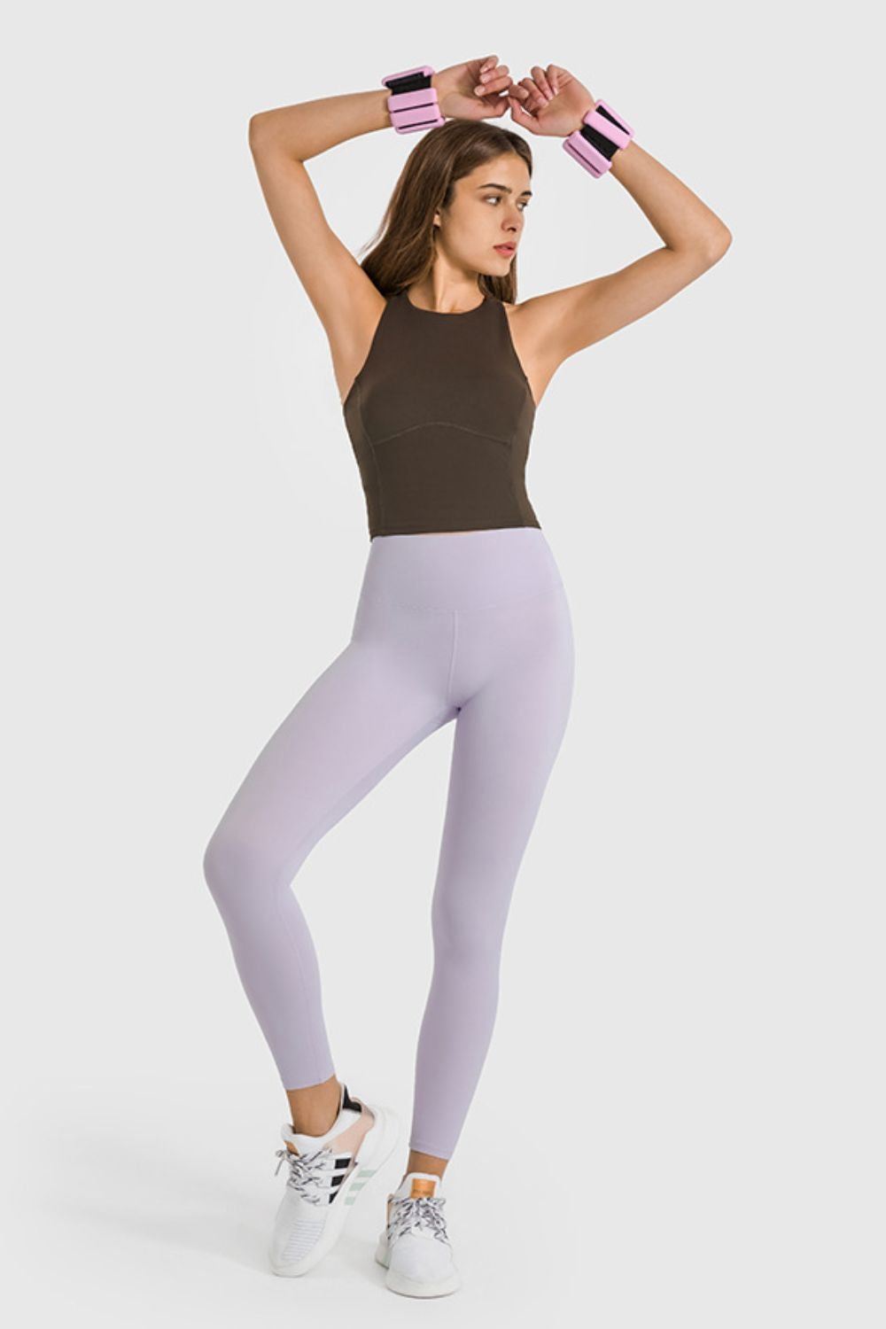 Model poses with arms overhead in light lavender high-waist ankle-length yoga leggings featuring a smooth, stretchy, fitted silhouette and clean construction.