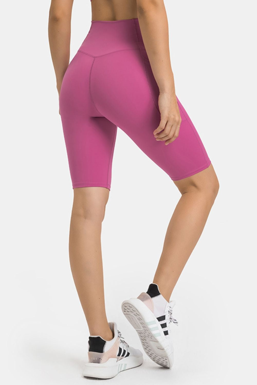 Model poses in magenta high-waist biker shorts with a fitted, stretchy silhouette, smooth seamed construction, and side pockets.