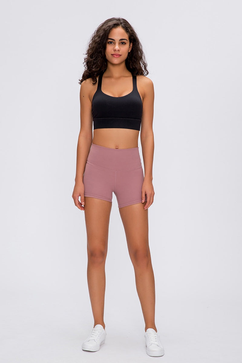 Model stands facing forward in mauve Stitch Active Shorts with a high-rise waistband, fitted stretch silhouette, and clean basic construction.