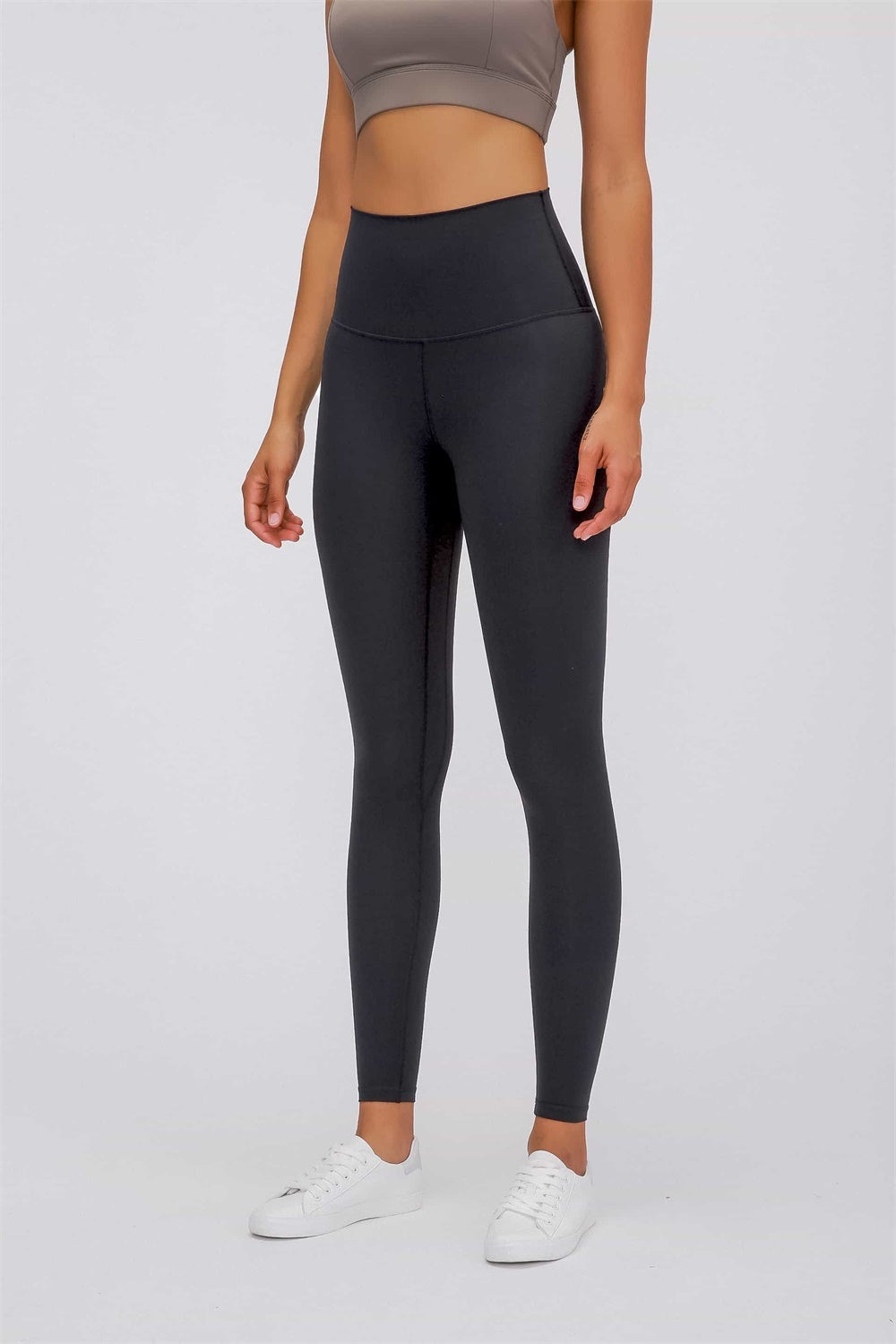 Model stands with arms relaxed, wearing black ultra-soft high-waist leggings with a wide elastic waistband, smooth fitted silhouette, and ankle-length construction.