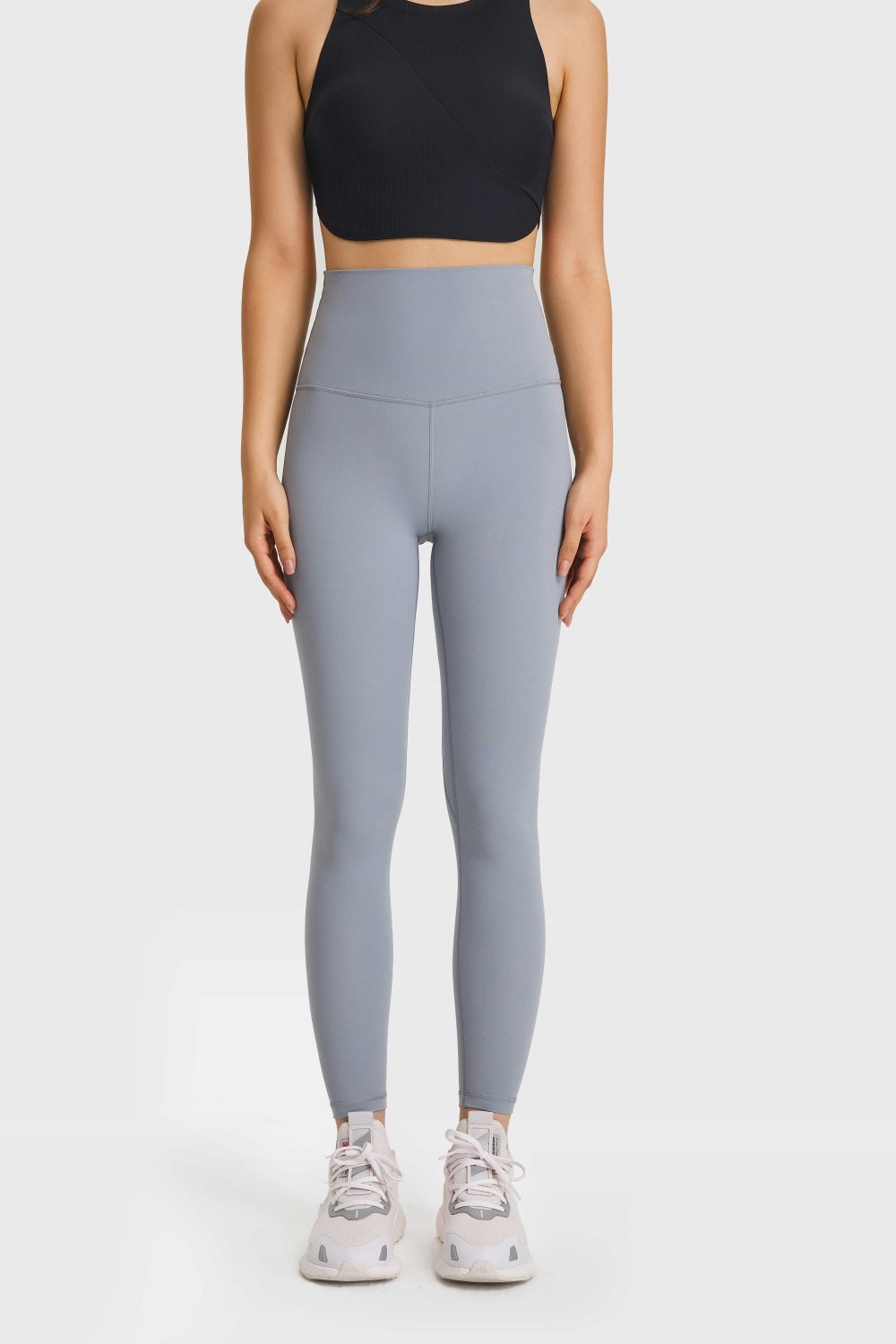 Model stands facing forward in light gray Ultra Soft High Waist Leggings with a smooth, stretchy fit, wide elastic waistband, stitched seams, and tapered full-length silhouette.