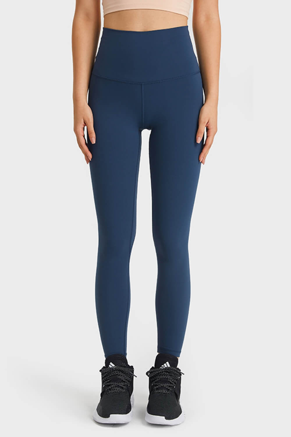 A model stands front-facing in navy Ultra Soft High Waist Leggings with an elastic waistband, smooth stretch fabric, slim full-length silhouette, and front center seam.