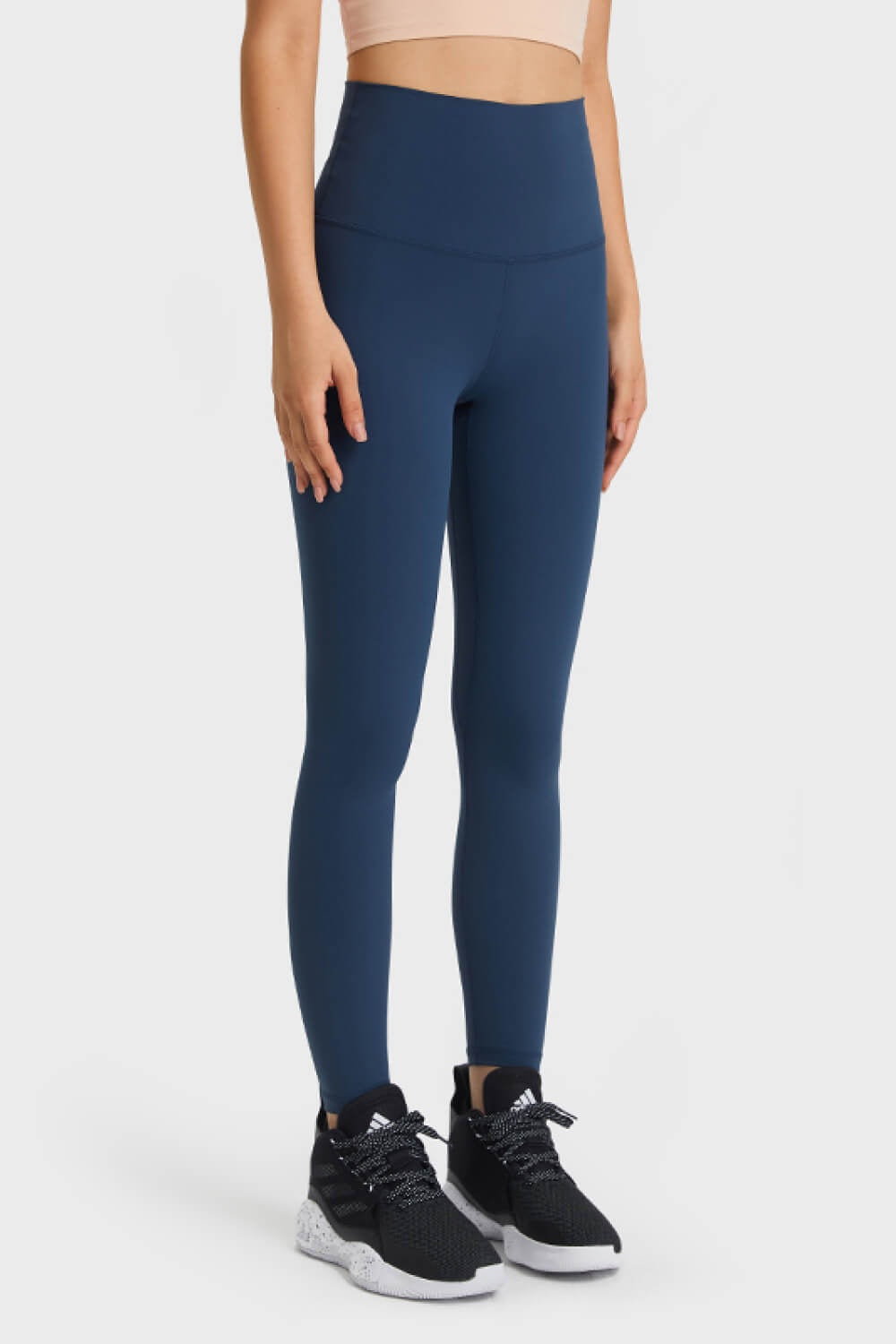 Model standing in navy blue ultra soft high waist leggings with a smooth elastic waistband, long fitted silhouette, and visible front seam construction.