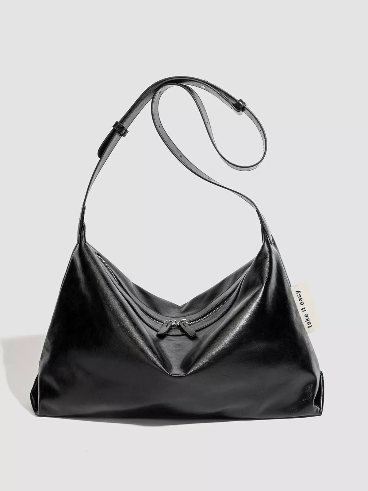 Black glossy PU leather slouchy shoulder bag with a soft, relaxed silhouette, long strap, and double-zip top closure.