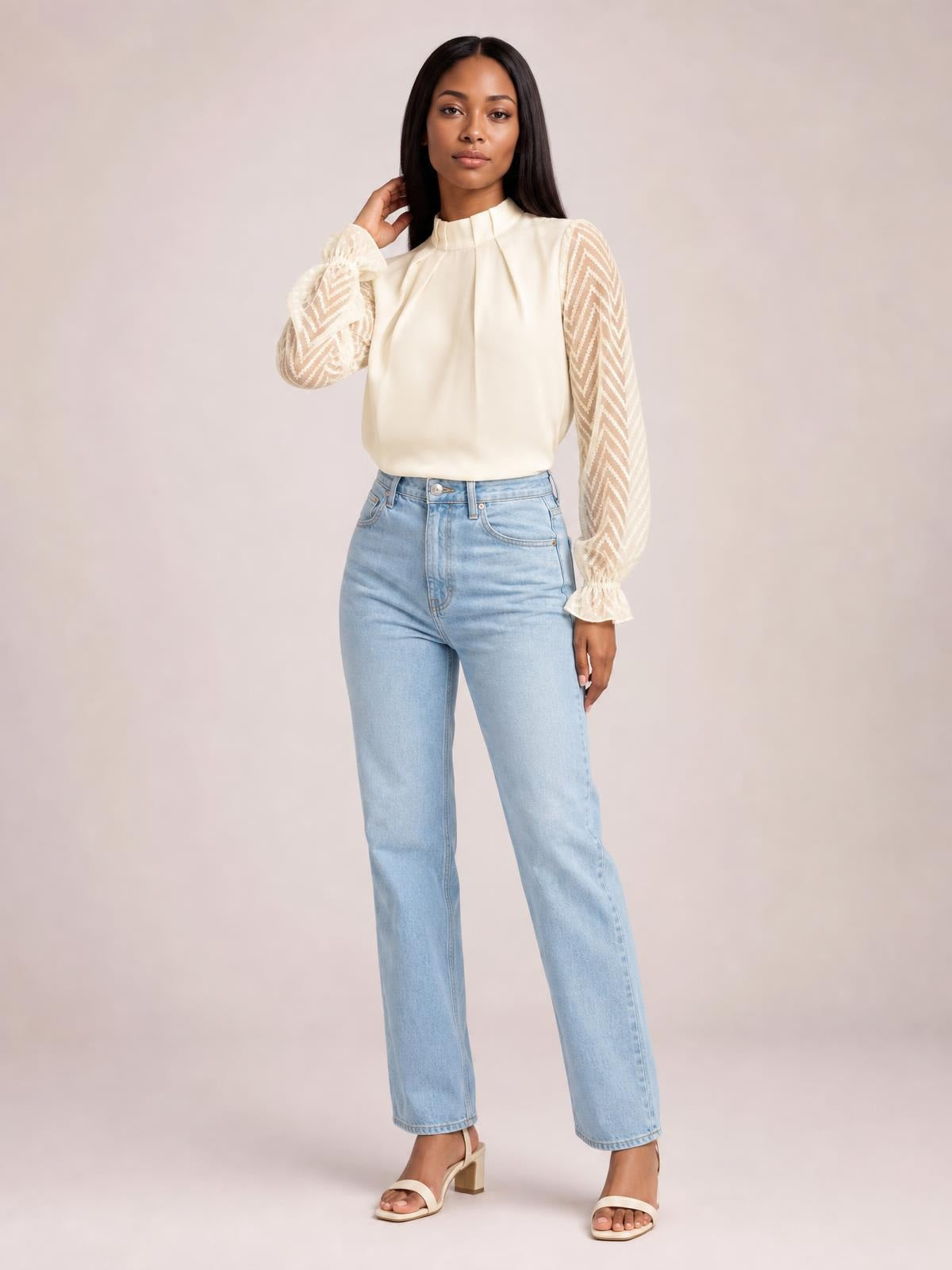 Model wearing an ivory mock neck blouse with ruffled flounce sleeves, sheer chevron-patterned panels, gathered cuffs, and a relaxed silhouette.