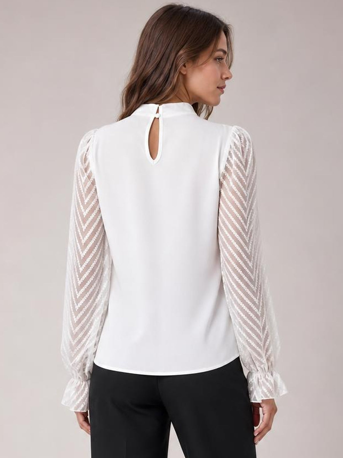 A model shows the back of a white mock neck blouse with a straight silhouette, keyhole closure, sheer chevron sleeves, and ruffled flounce cuffs.