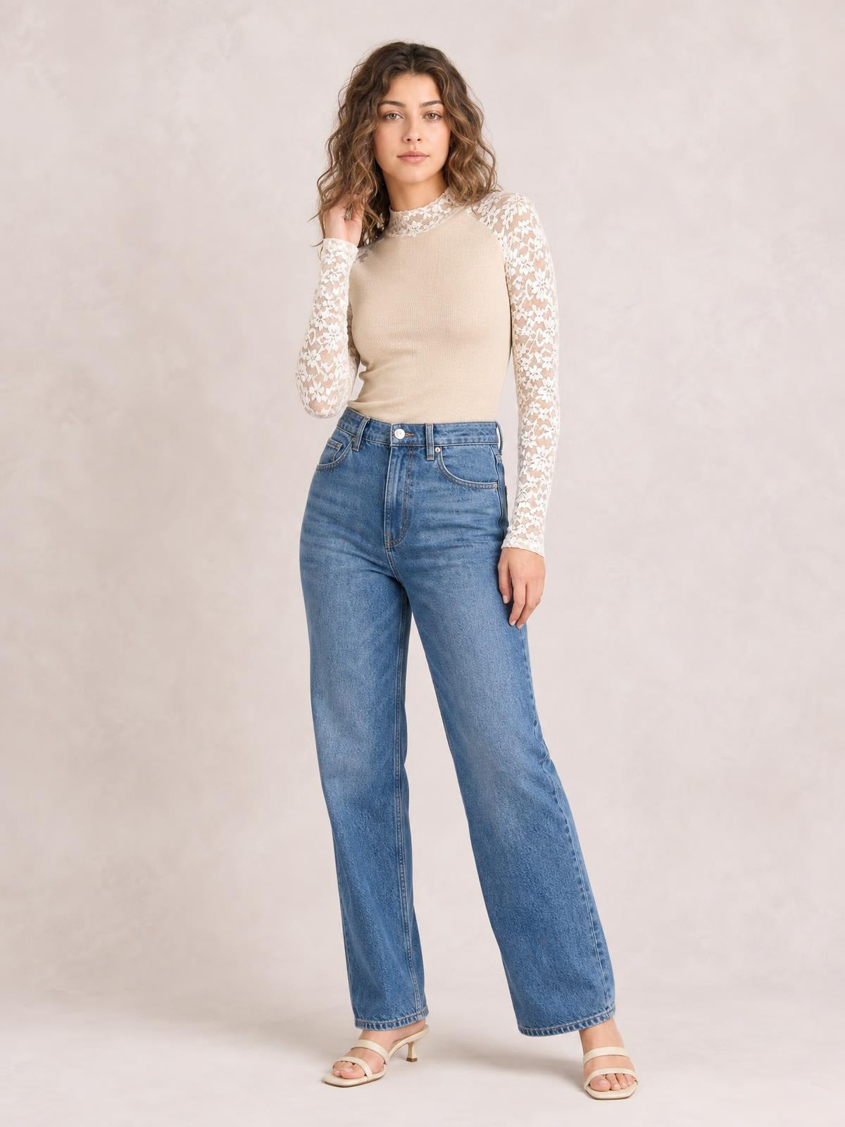 Model poses in a beige mock neck long sleeve T-shirt with semi-sheer floral lace sleeves and collar, fitted silhouette, and delicate patchwork details.