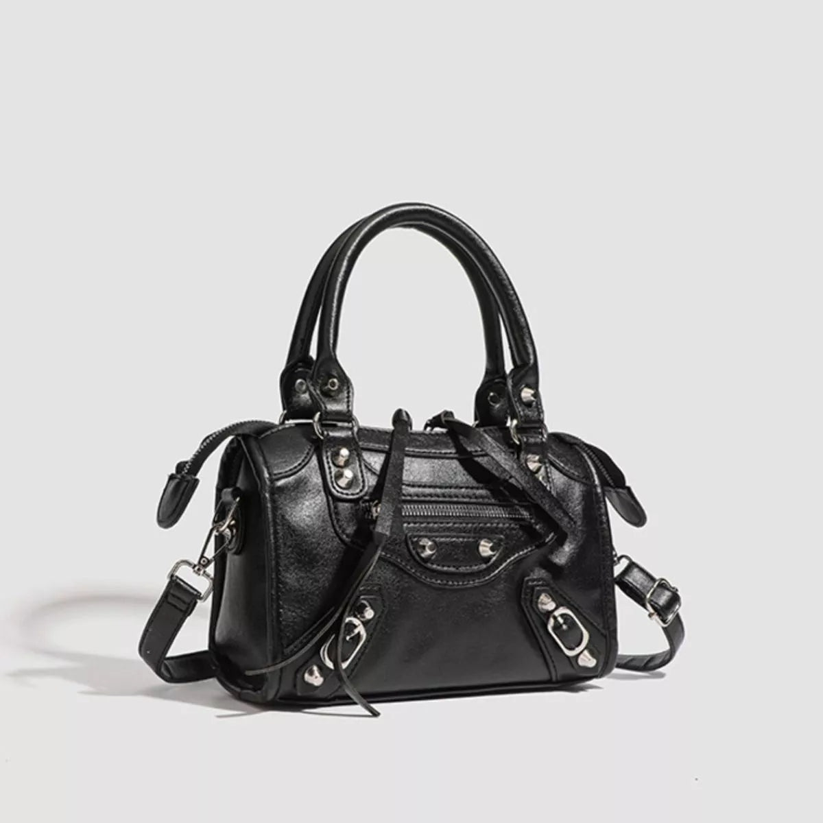 Small black PU leather motorcycle-style crossbody bag with dual handles, silver studs and hardware, multiple zippered compartments, and a detachable shoulder strap.