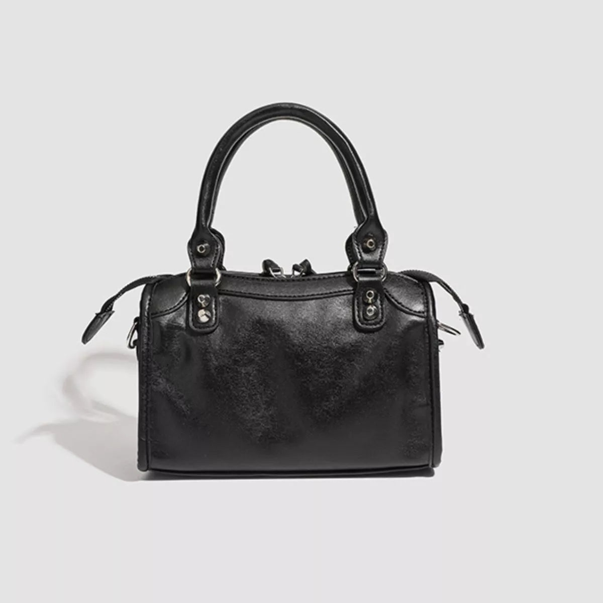 Small black PU leather motorcycle-style crossbody bag with twin top handles, a structured rectangular silhouette, zip-top closure, and side strap attachments.
