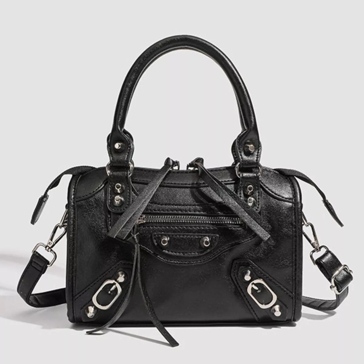 Small black PU leather motorcycle-style crossbody bag with top handles, silver hardware, zip pockets, decorative straps, and a structured silhouette.