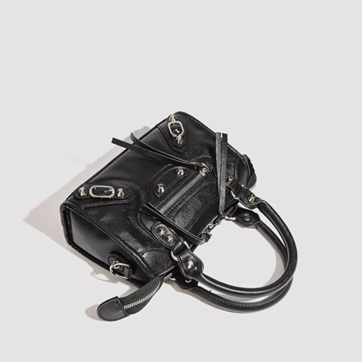 Small black PU leather motorcycle-style crossbody bag with studded accents, multiple zippered pockets, metal hardware, and twin rounded handles.