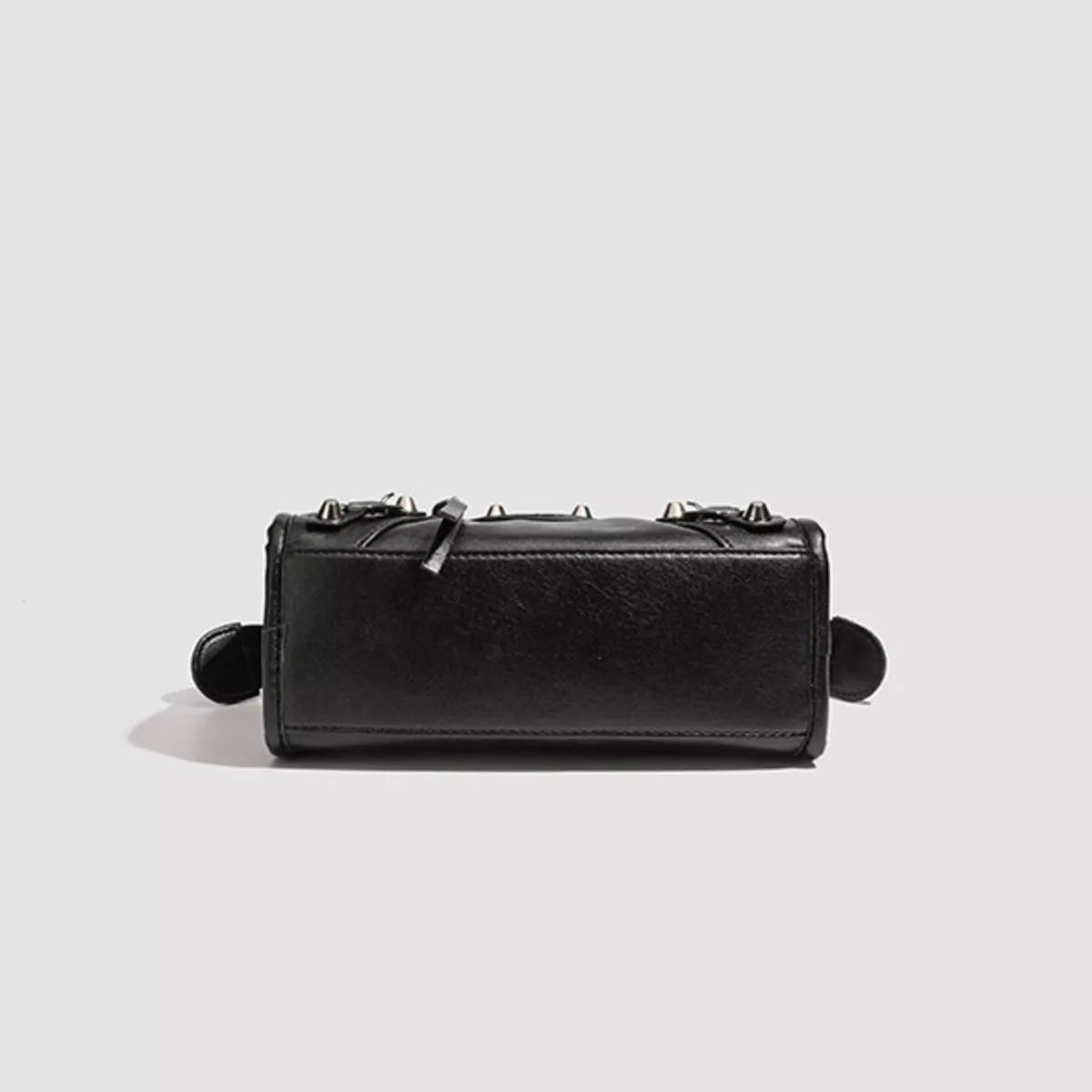 Small black PU leather crossbody bag with a structured rectangular silhouette, top-edge studded detailing, stitched construction, and side tabs.