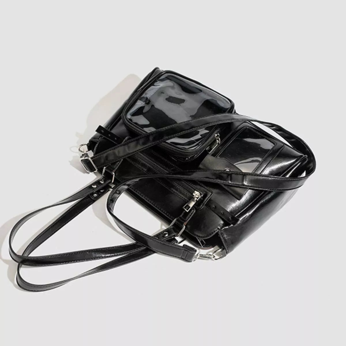 Black medium PU leather shoulder bag with multiple zippered pockets, clear window panels, and long adjustable straps in a structured silhouette.