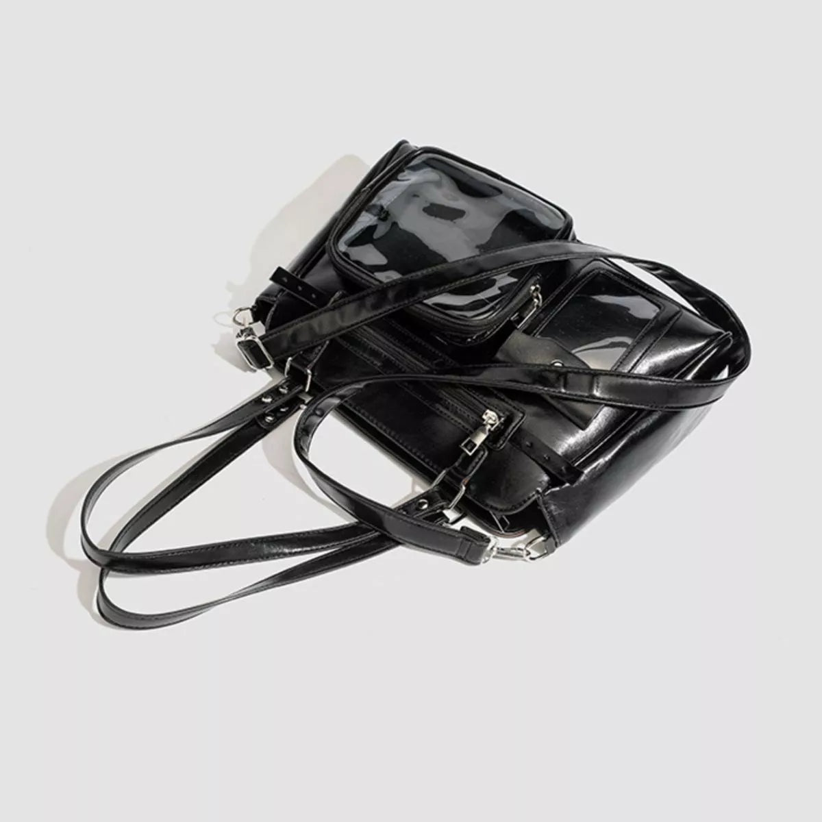 A medium black PU leather shoulder bag with multiple zippered pockets, clear window panels, structured construction, and long adjustable straps.