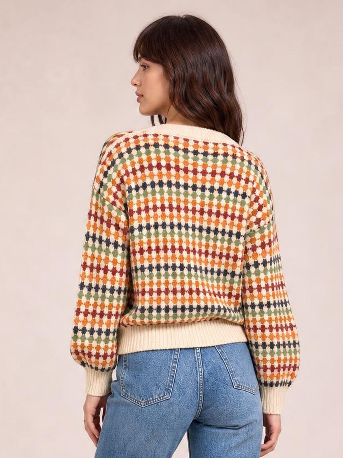Model shown from behind in a relaxed multicolour dotty pattern knit cardigan with long sleeves, ribbed cuffs and hem, turning to the side.
