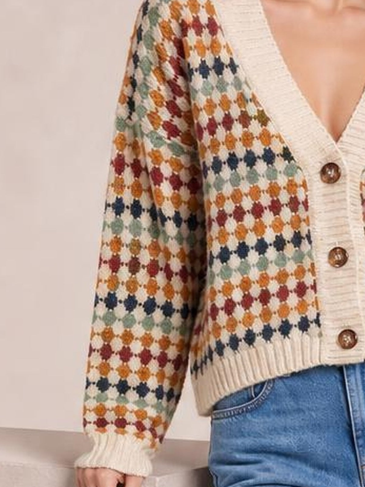 Model wears a multicolour dotty pattern knit button-front cardigan with long sleeves, ribbed edges, and a relaxed silhouette.