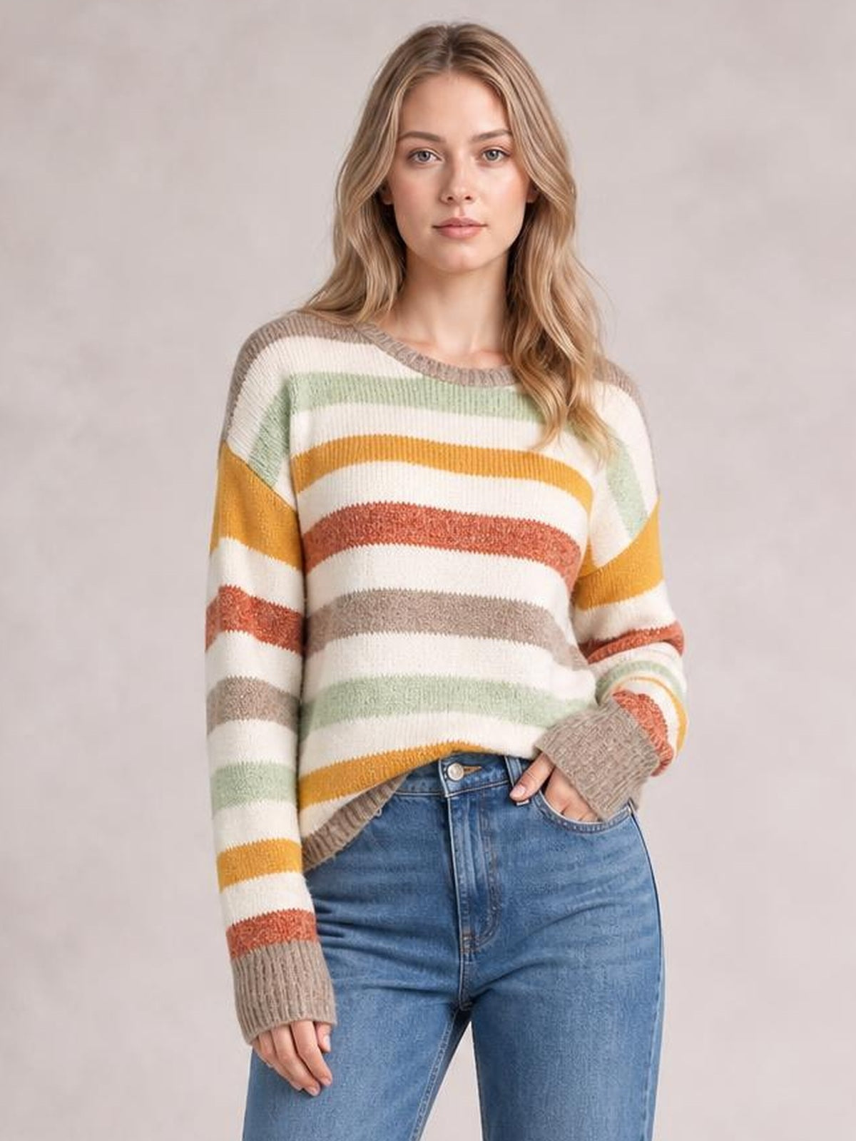 Model wearing a multicolour stripe drop shoulder crew neck sweater with a relaxed silhouette, ribbed trim, and one hand resting in her jeans pocket.