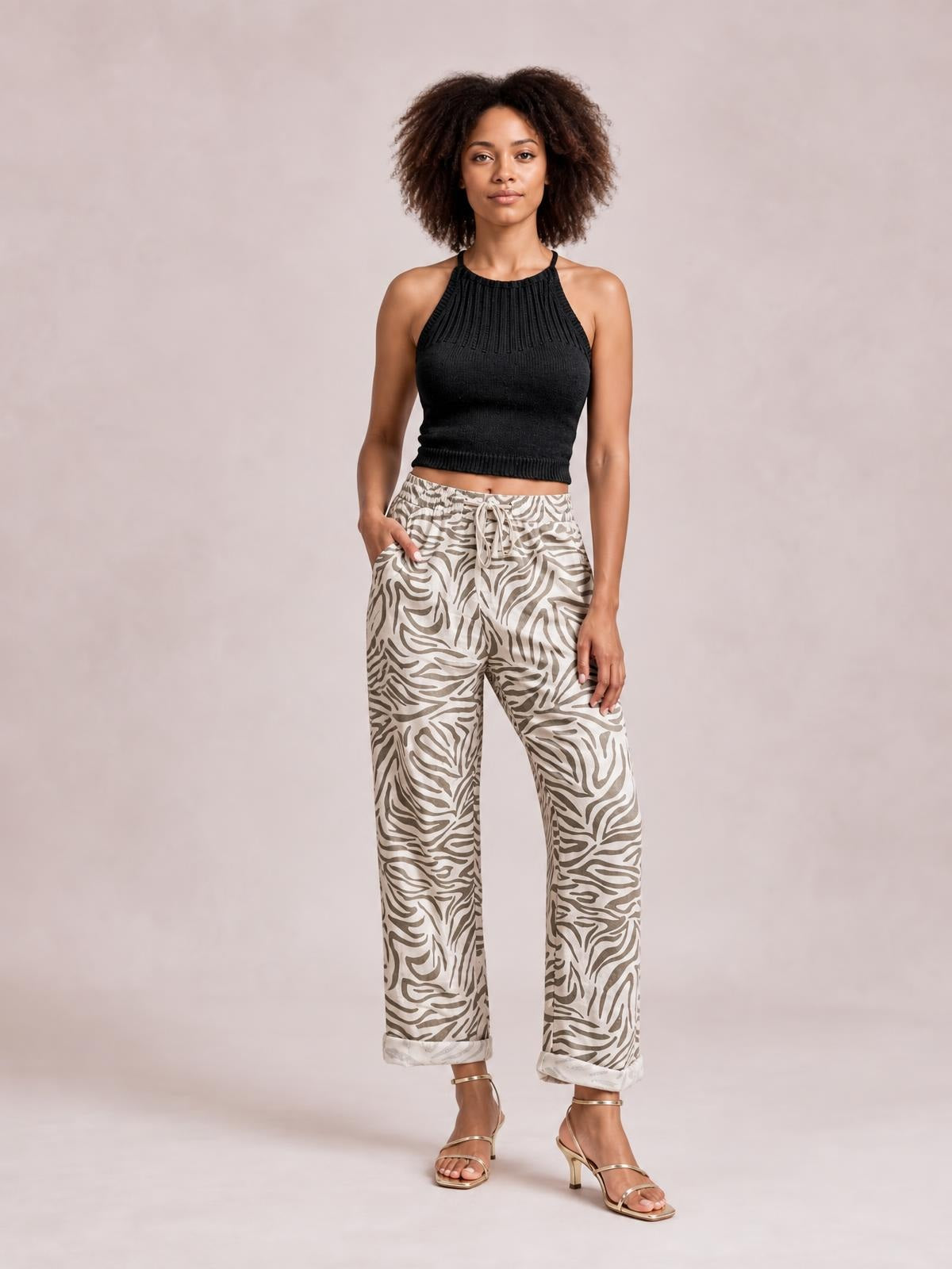 Model stands with one hand in a pocket, wearing multicolour zebra-pattern pants with an elastic drawstring waist, wide cropped legs, and rolled hems.