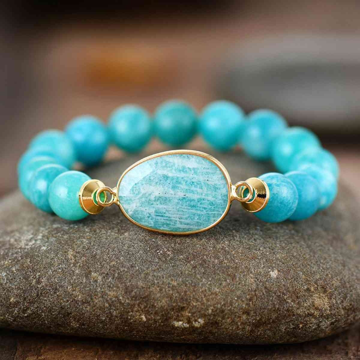 Natural stone beaded bracelet with turquoise round beads, a marbled oval centerpiece, and gold-tone connector details in a flexible bracelet silhouette.