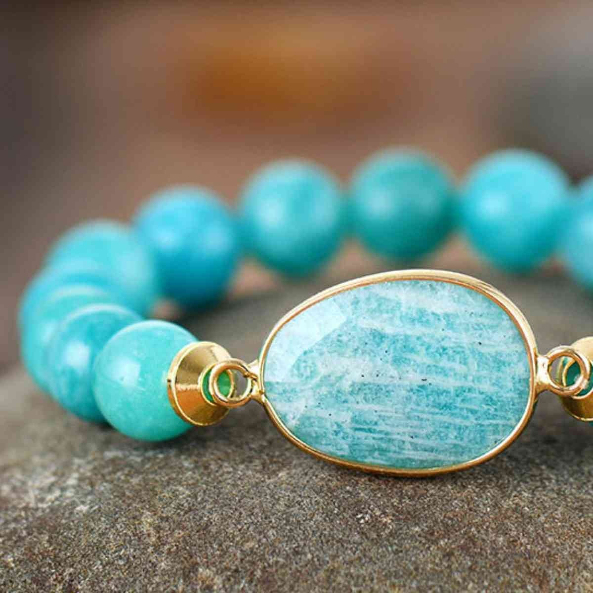 Natural stone beaded bracelet with turquoise round beads and a large oval blue-green stone centerpiece in a gold-tone setting.