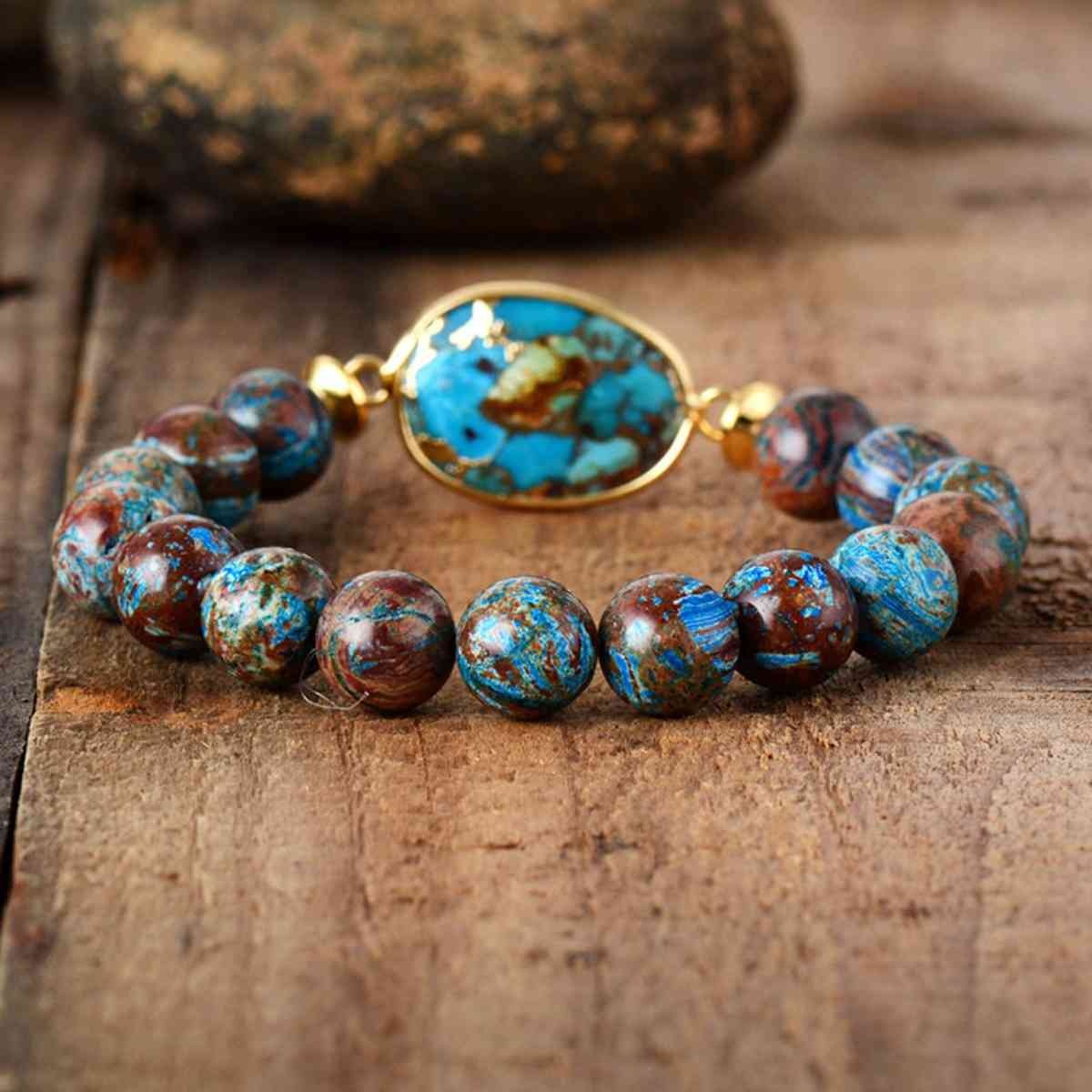 Natural stone beaded bracelet with multicolored round beads, a turquoise oval centerpiece, and gold-tone accents in a bold stretch design.