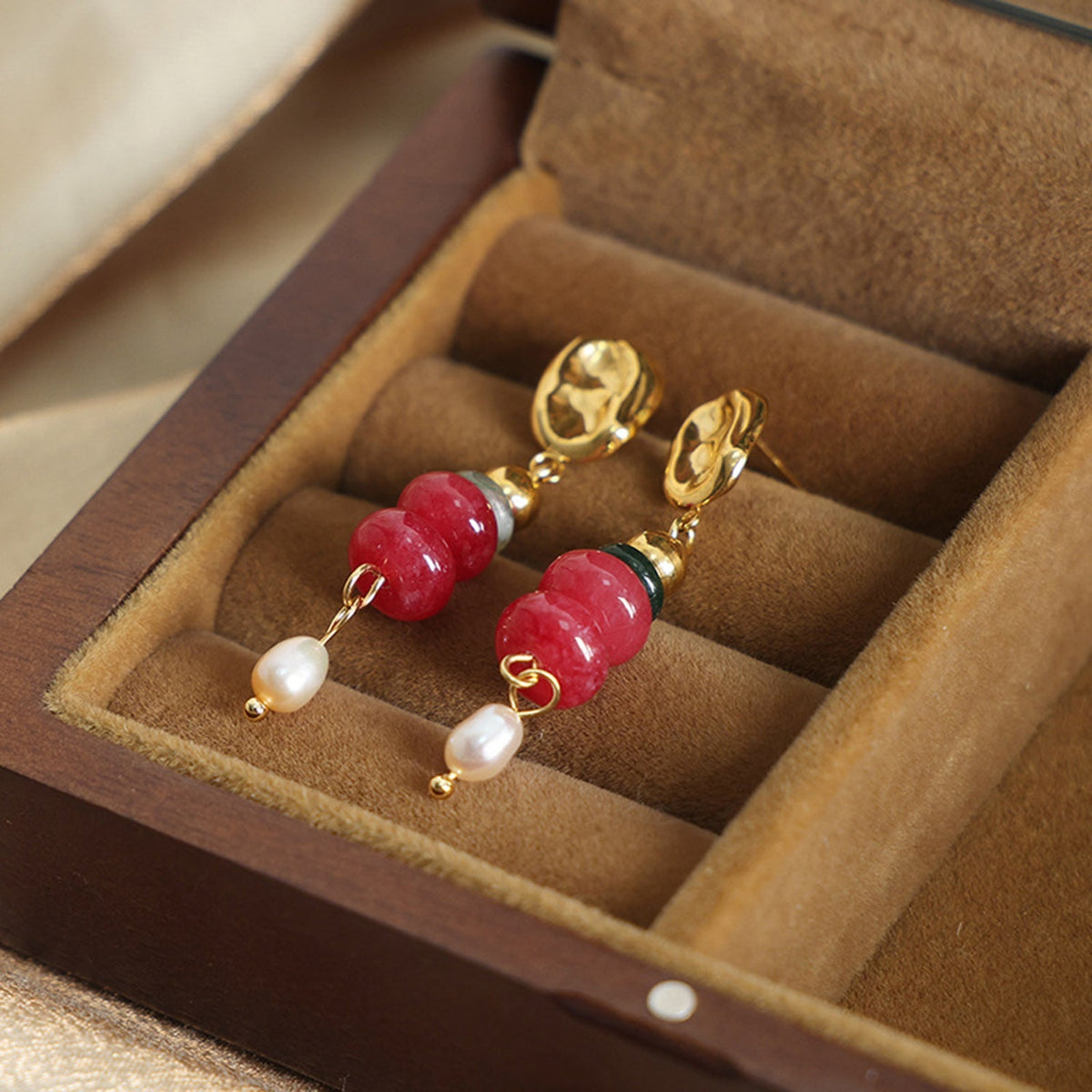 Natural stone freshwater pearl dangle earrings feature glossy red stone beads, white pearl drops, and gold-plated oval studs in an elegant drop silhouette.