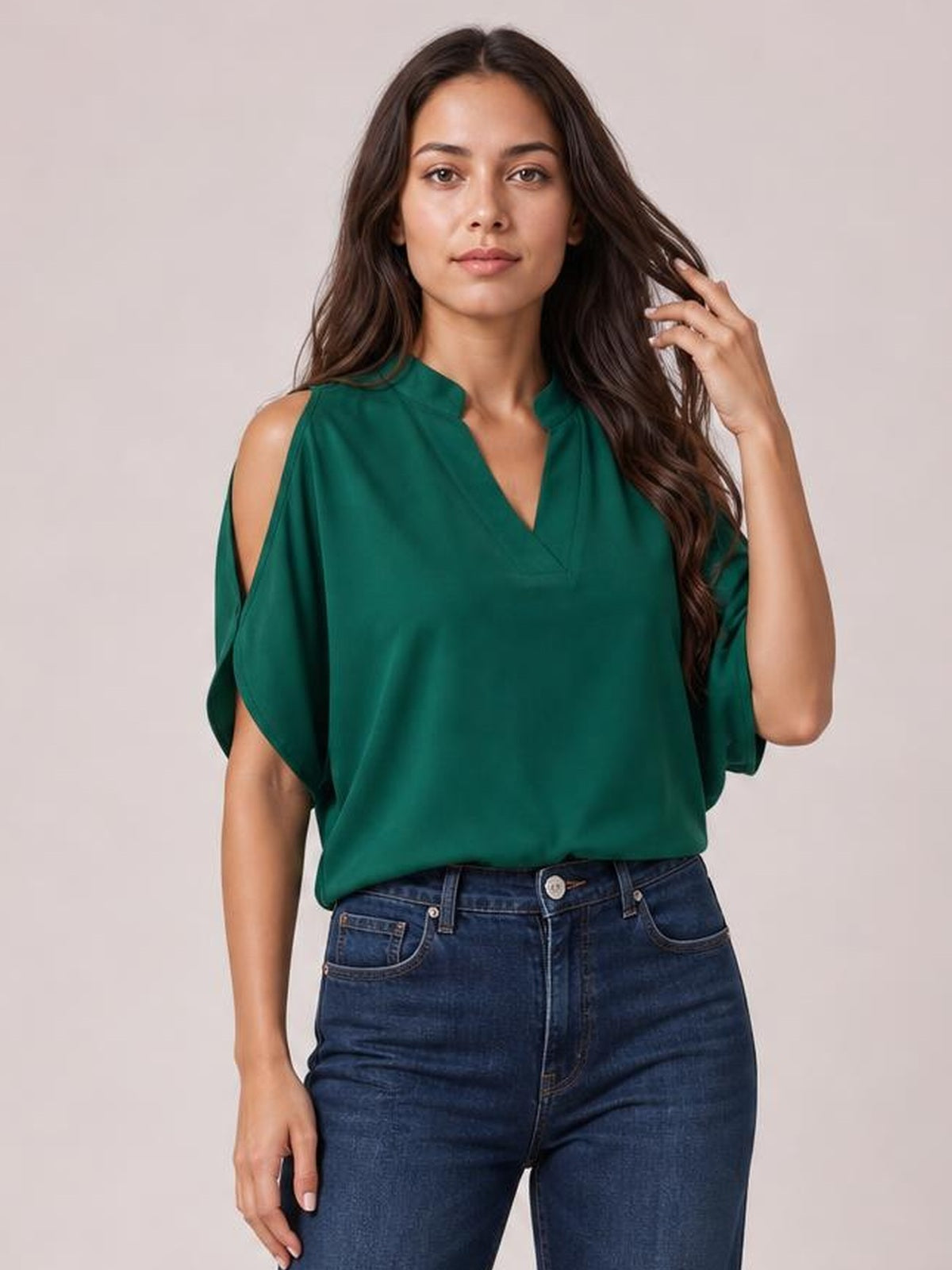 A model poses in a deep green notched cold shoulder blouse with shoulder cutouts, a relaxed draped silhouette, and short loose sleeves.