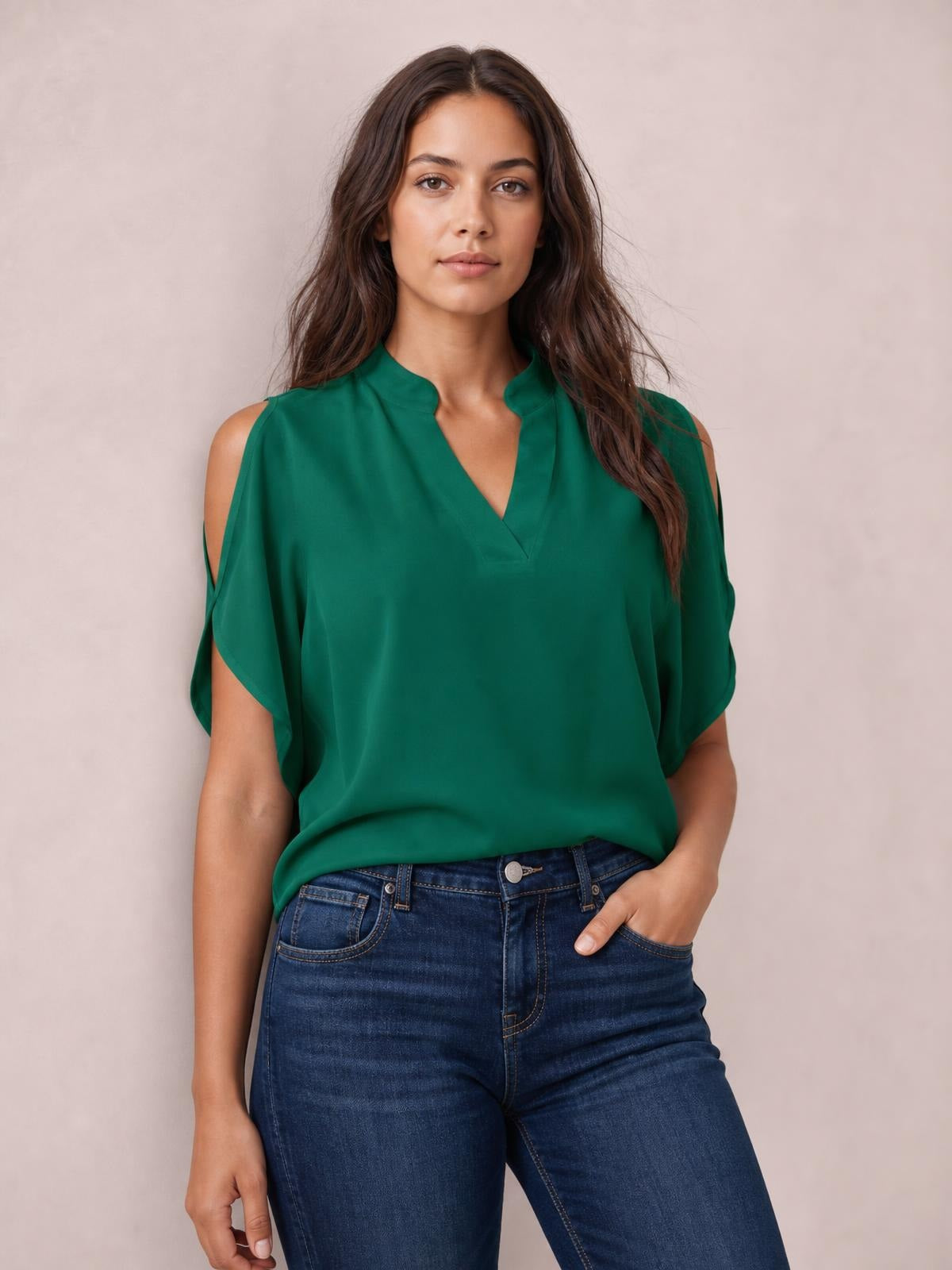 Model wears a green notched cold shoulder blouse with shoulder cutouts, a relaxed silhouette, short split sleeves, and a softly draped opaque construction.