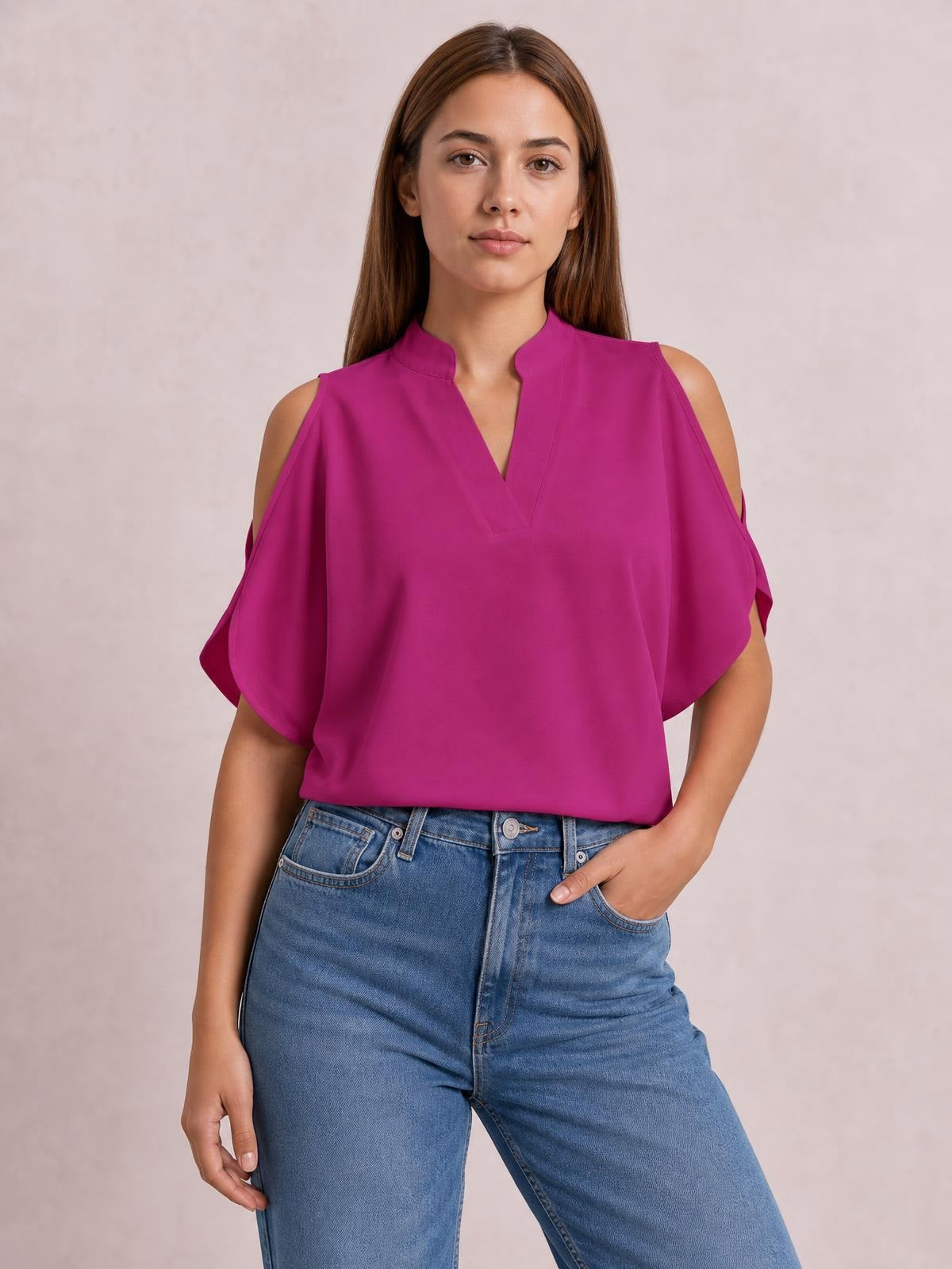 Model wears a magenta notched cold shoulder blouse with a V-slit neckline, loose draped silhouette, and flowing short sleeves.