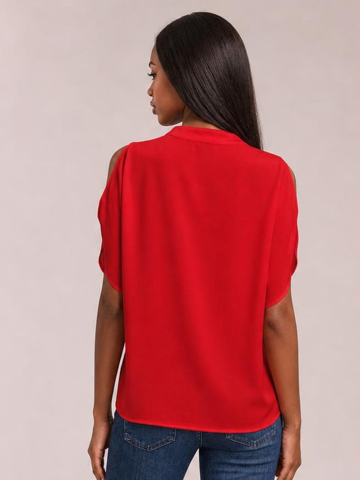 A model stands facing away in a bright red Notched Cold Shoulder Blouse with exposed shoulders, short sleeves, a relaxed silhouette, and curved hem.