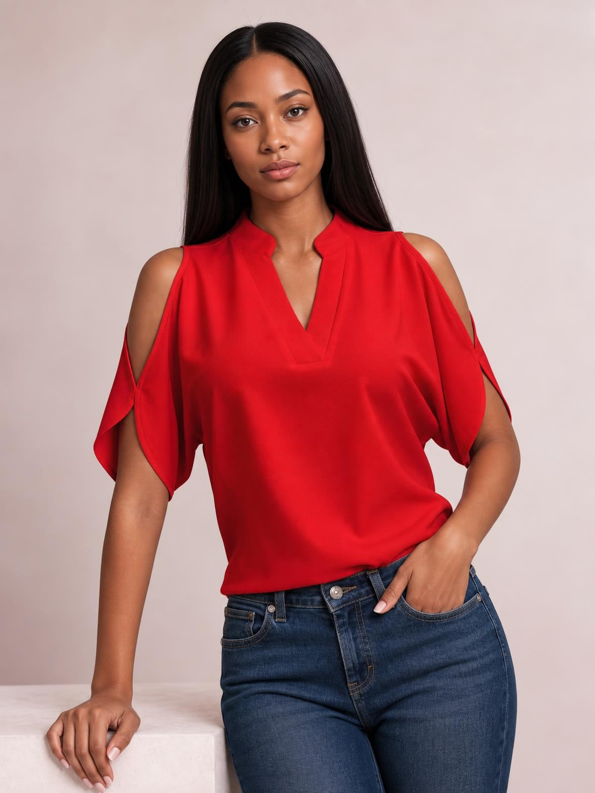 Model wearing a red notched cold shoulder blouse with an opaque draped silhouette, cutout shoulders, and flowing short sleeves.