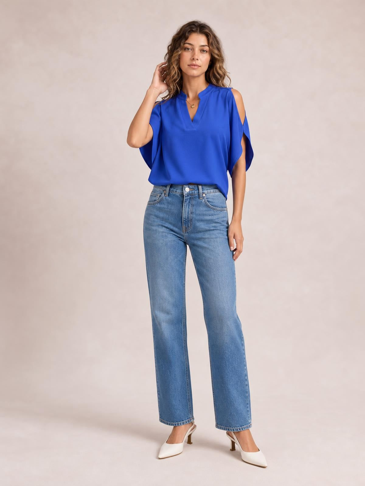 Model poses in a vibrant blue notched cold shoulder blouse with a relaxed silhouette, flowing sleeves, and shoulder cutouts.