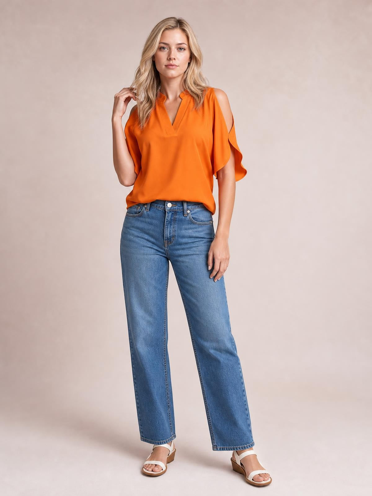 Model wears an orange notched cold shoulder blouse with a V neckline, flutter sleeves, and a relaxed straight silhouette, posing with one hand raised.