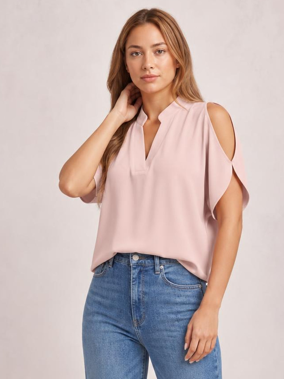 Model wearing a pale pink Notched Cold Shoulder Blouse with a relaxed silhouette, split neckline, cutout shoulders, and short flutter sleeves.