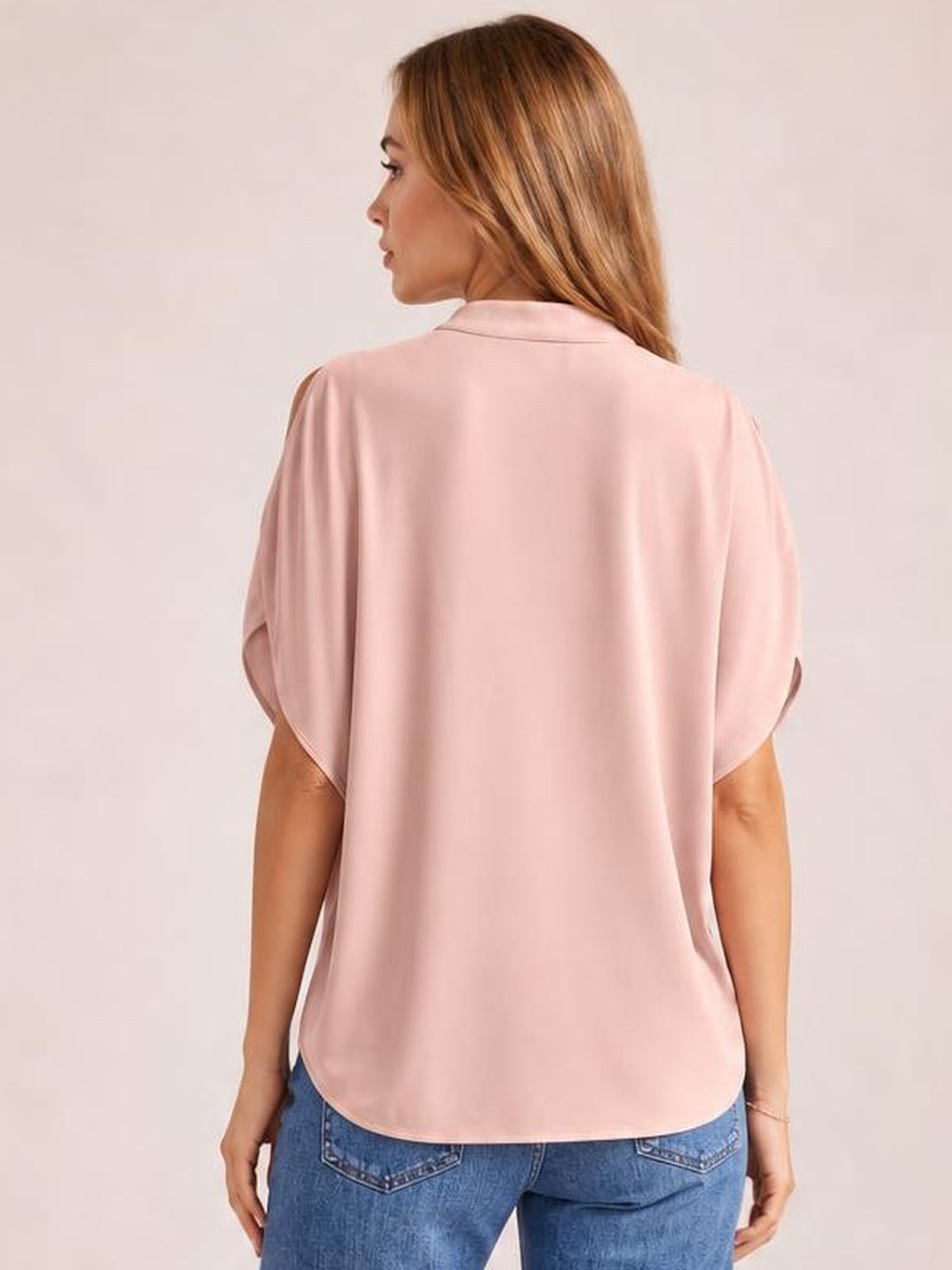 Back view of a model wearing a pink Notched Cold Shoulder Blouse with relaxed short sleeves, shoulder cutouts, a smooth silhouette, and curved hem.