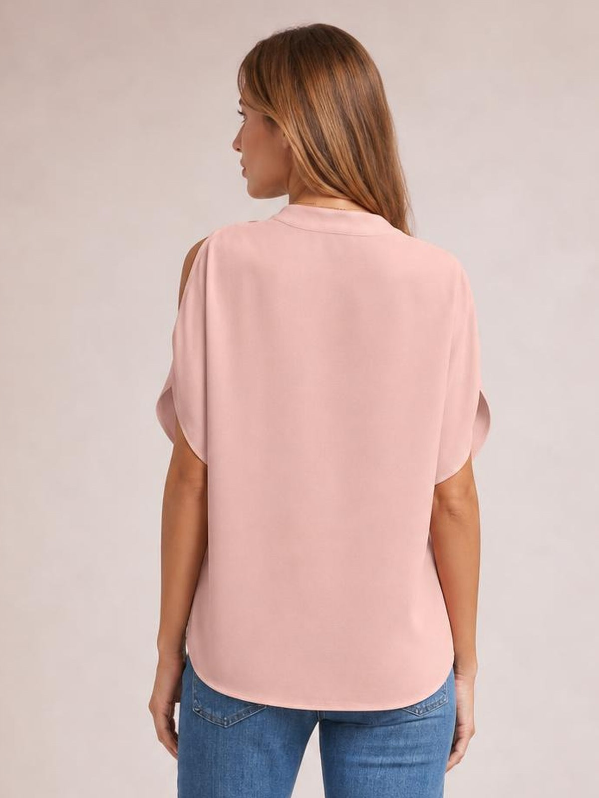 Model shown from behind wears a pink opaque cold shoulder blouse with half sleeves, relaxed straight silhouette, shoulder cutouts, and a rounded hem.