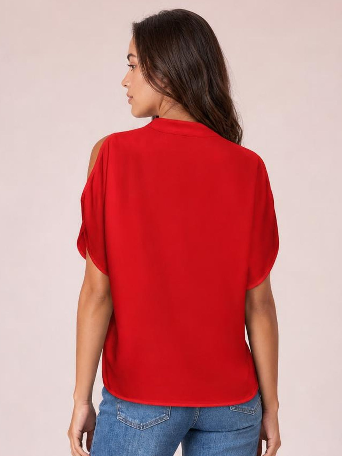 Model shown from the back in a relaxed red cold shoulder blouse with short half sleeves, shoulder cutouts, a smooth opaque fabric, and a curved hem.