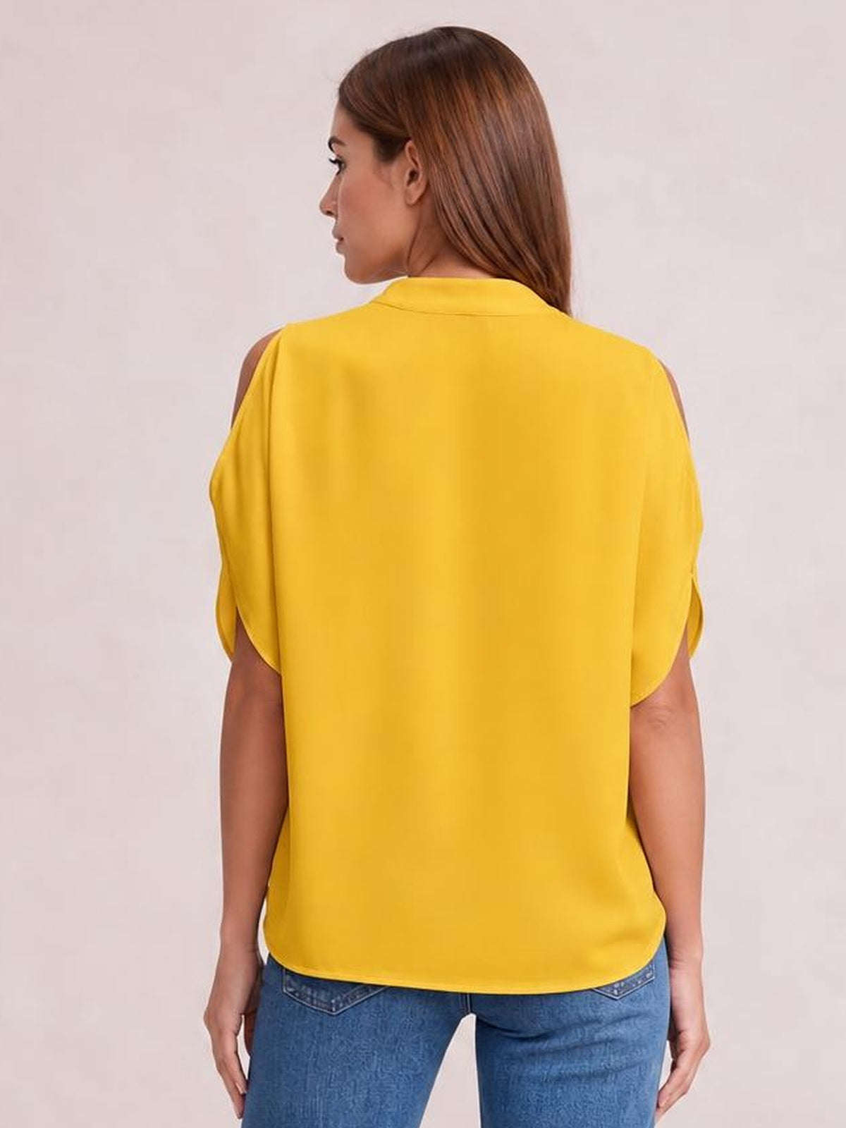 Back view of a model wearing a bright yellow cold shoulder blouse with half sleeves, shoulder cutouts, a loose straight silhouette, and curved hem.