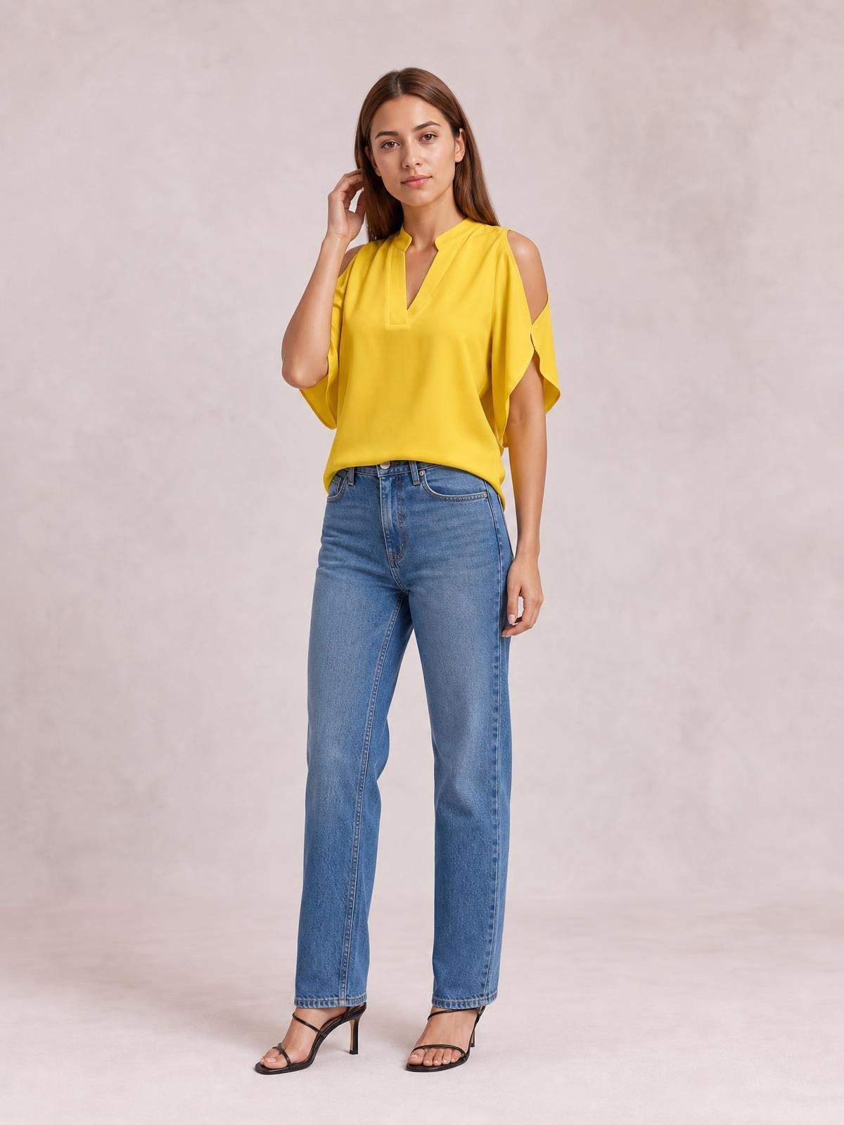 A model poses with one hand near her hair, wearing a bright yellow blouse with a notched neckline, cold-shoulder cutouts, and loose half sleeves.