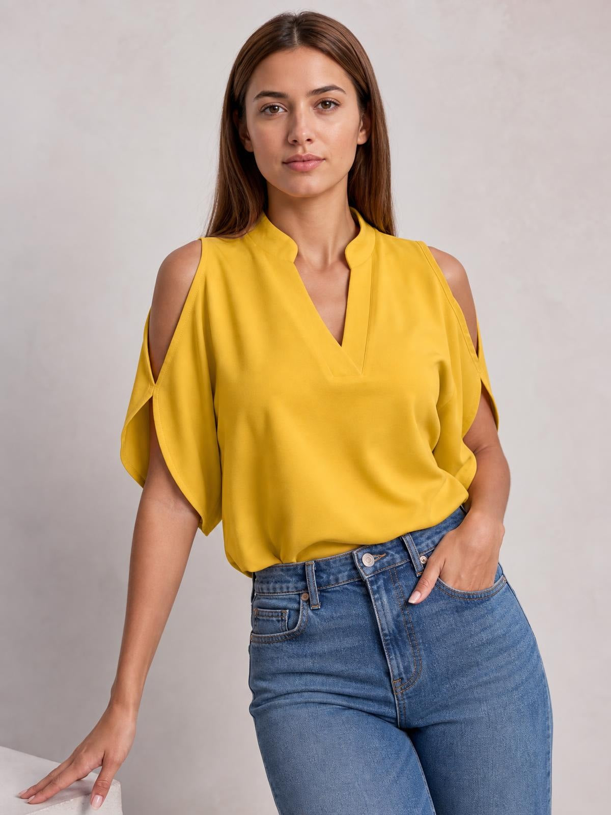 A model wears a mustard-yellow opaque blouse with a notched V-neck, cold-shoulder cutouts, draped half sleeves, and a relaxed silhouette.