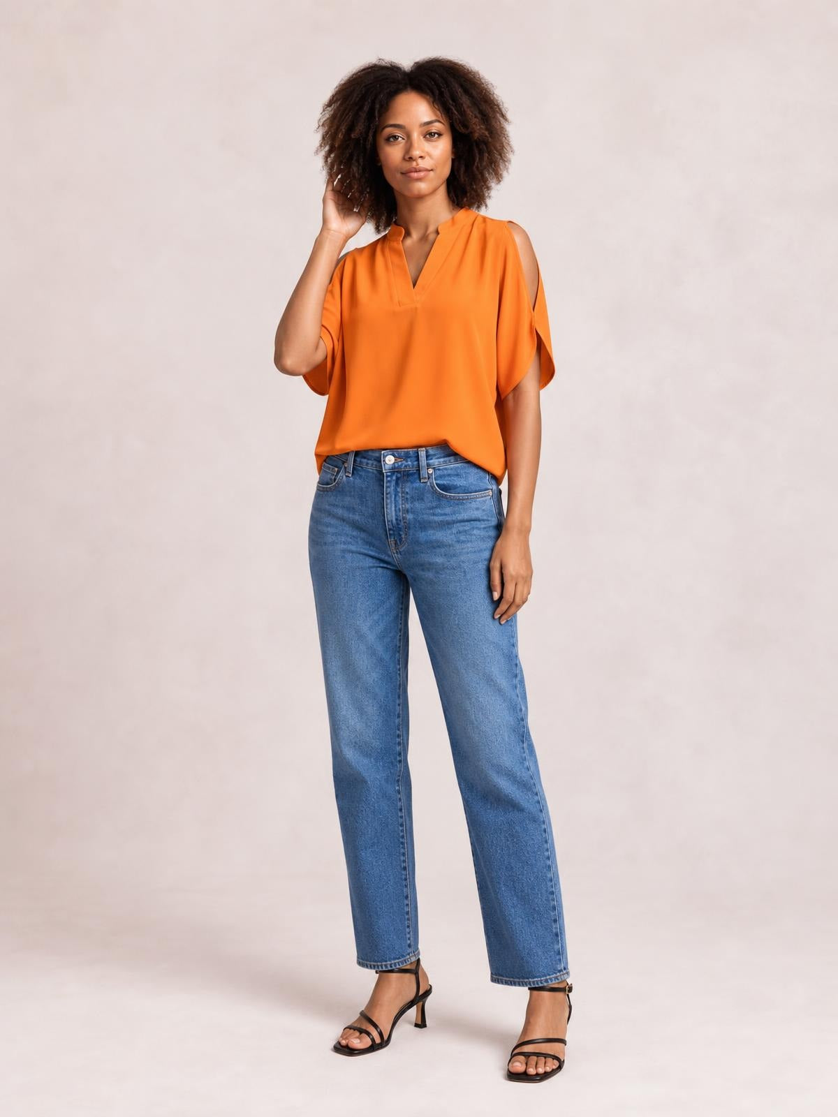 Model poses in an orange notched cold shoulder blouse with loose half sleeves, shoulder cutouts, and a relaxed straight silhouette.
