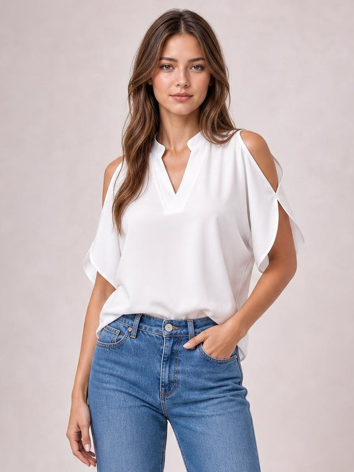 Model wears a white notched cold shoulder blouse with half sleeves, exposed shoulders, a relaxed straight silhouette, and her hand resting in her jeans pocket.