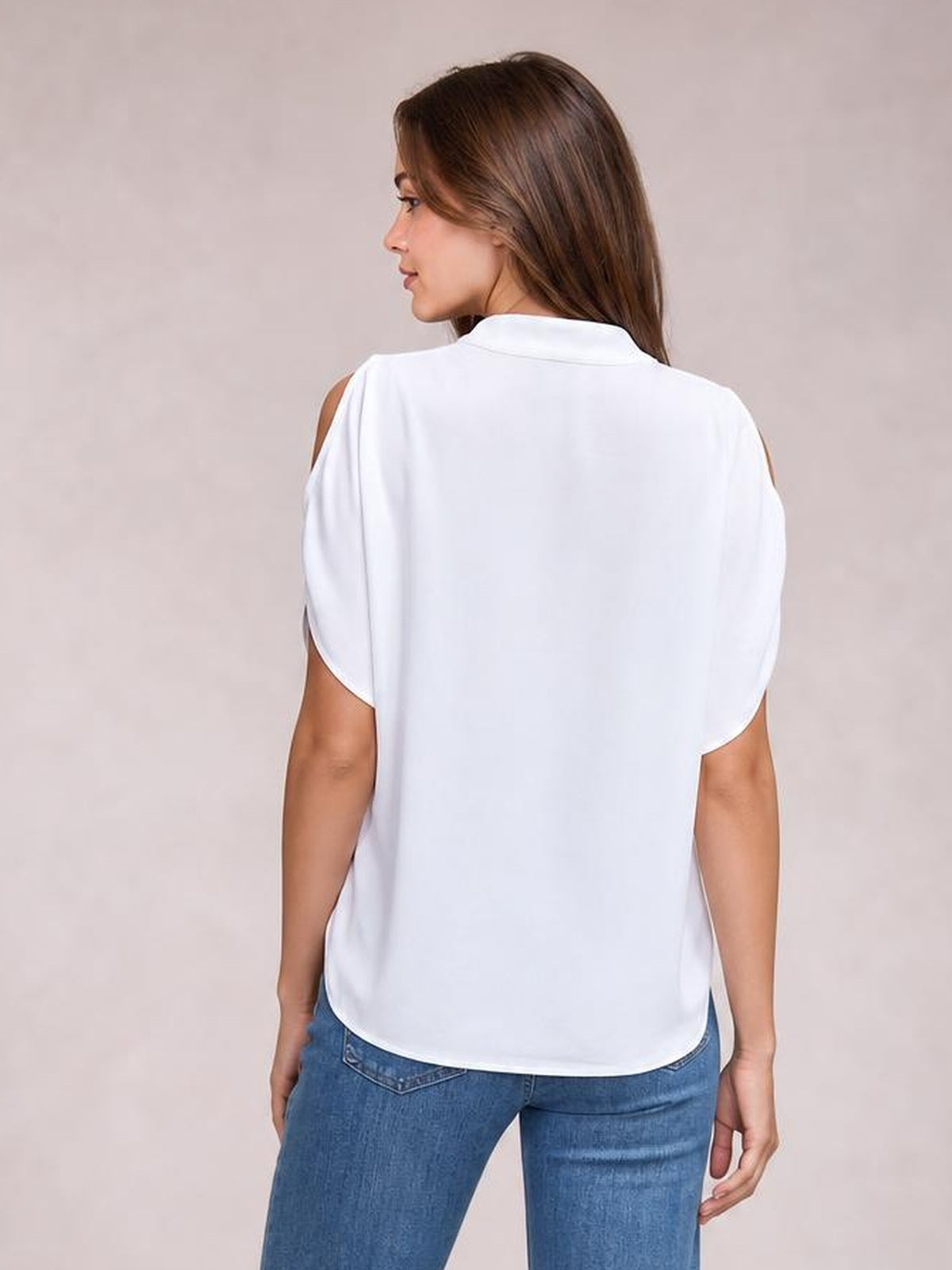 A model wears a white opaque cold shoulder blouse with half sleeves, open shoulder cutouts, a relaxed silhouette, and a curved hem, shown from the back.